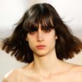 New York Fashion Week hair: Closeup shot of a woman with shoulder length dark hair with bangs