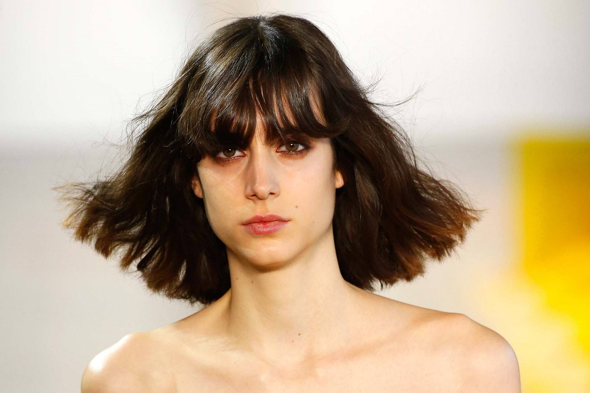New York Fashion Week hair: Closeup shot of a woman with shoulder length dark hair with bangs