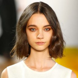 New York Fashion Week Hair: Closeup shot of a woman with a dark brown textured lob wearing a white dress