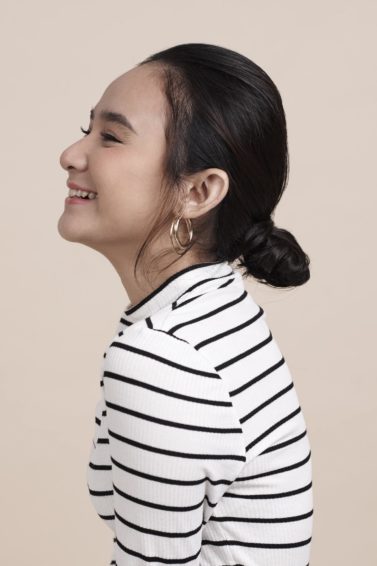 Romantic hairstyles for short hair: Side view shot of an Asian woman with short black hair in a low bun
