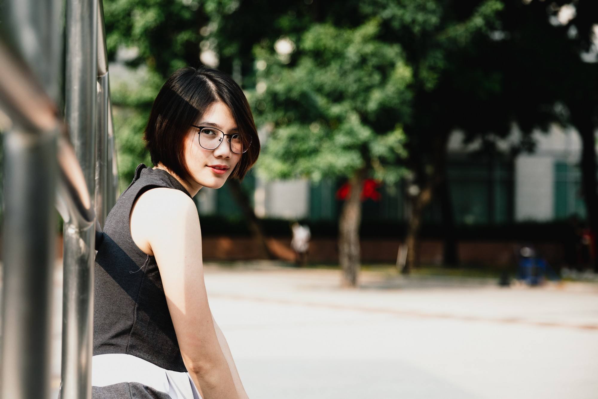 girl is wearing eyeglasses and is sitting outdoors