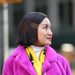 Side sweep hair: Closeup shot of an Asian woman with dark straight lob wearing a pink coat outdoors