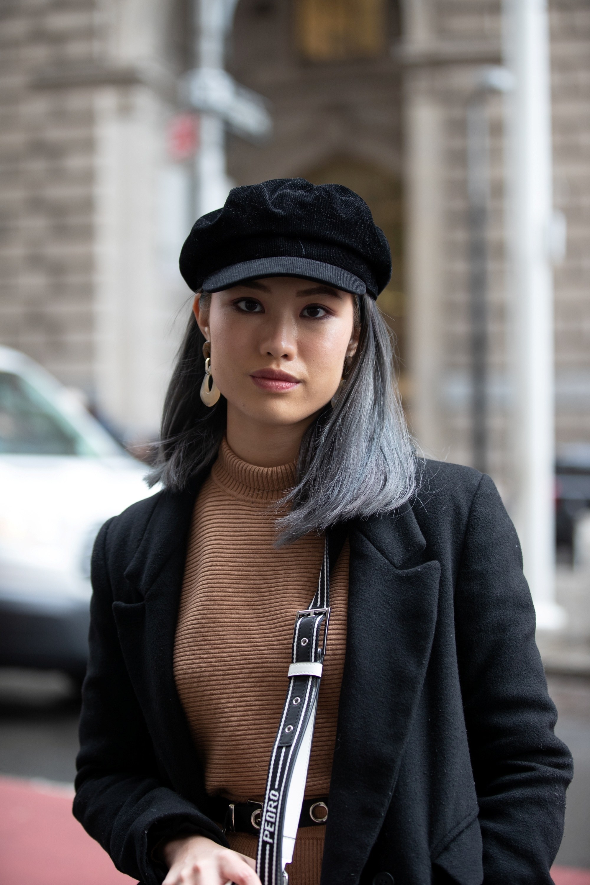 Street style hair inspiration: Woman with dip-dyed ash gray hair wearing a black hat and black jacket outdoors