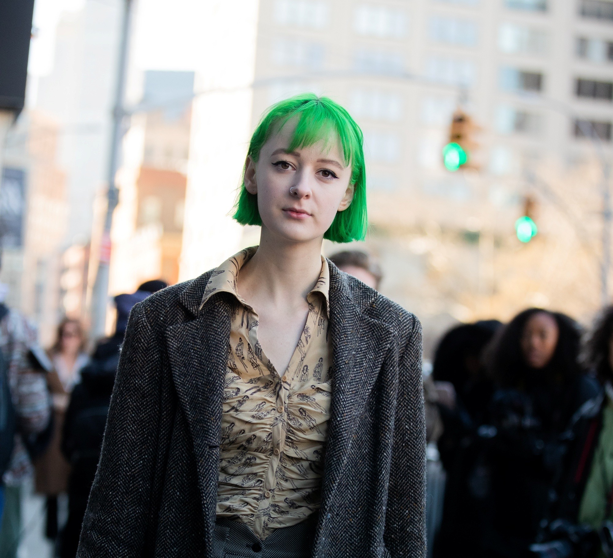 Street style hair inspiration: Woman with pale skin with a green short bob with bangs wearing dark jacket outdoors