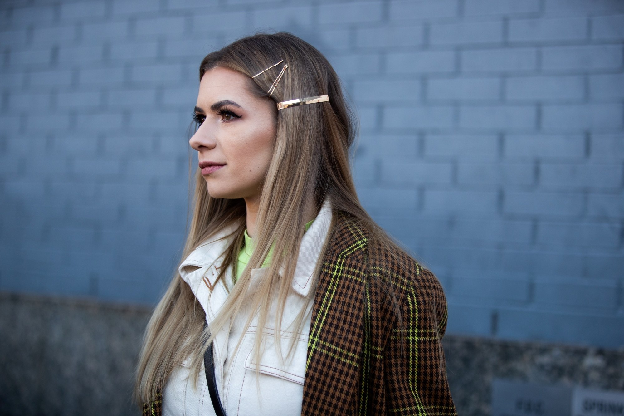 Street style hair inspiration: Woman with long straight blonde hair wearing hair clips and a brown jacket outdoors