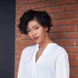 Boyish haircuts: Closeup shot of an Asian woman with short black curly hair wearing a white blouse