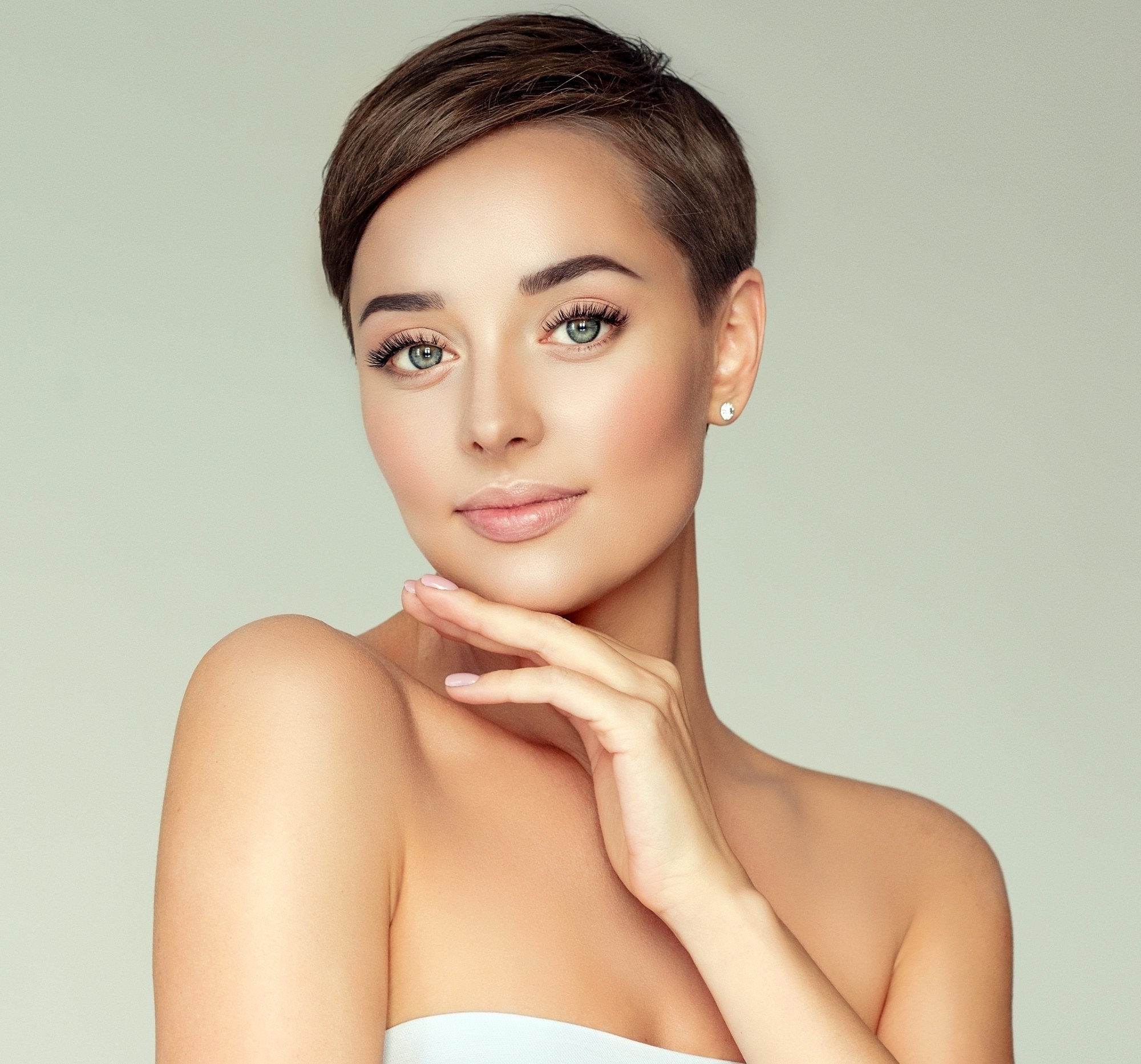 Short hairstyles for long faces: Closeup shot of a woman with short dark hair wearing a white tube top