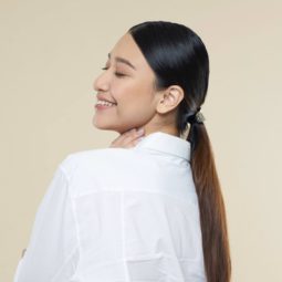 Sleek tied hair: Side view of an Asian woman with long dark hair in low ponytail wearing a white blouse