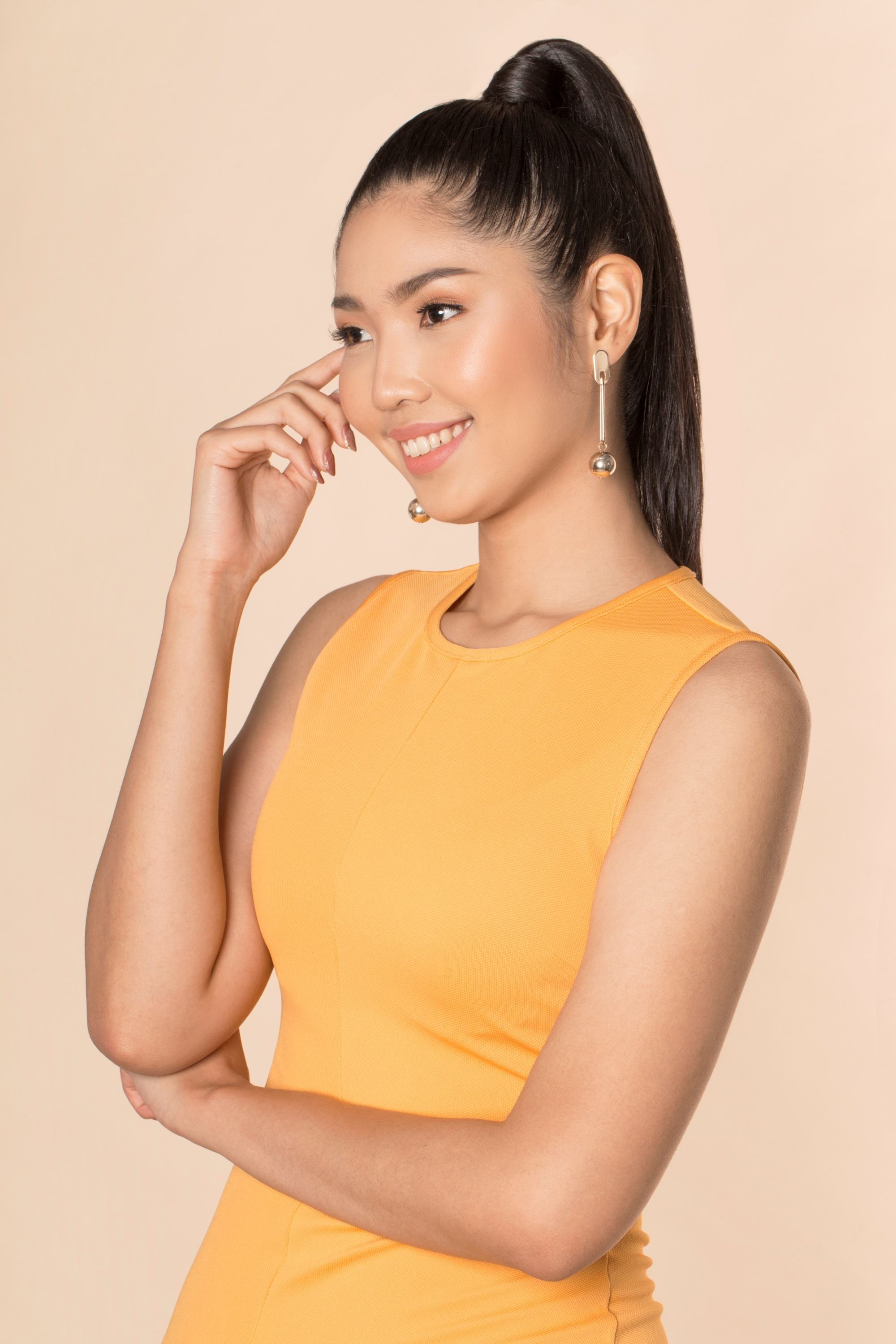 Sleek tied hair: Asian woman with long black hair in high ponytail wearing a mustard-colored sleeveless dress