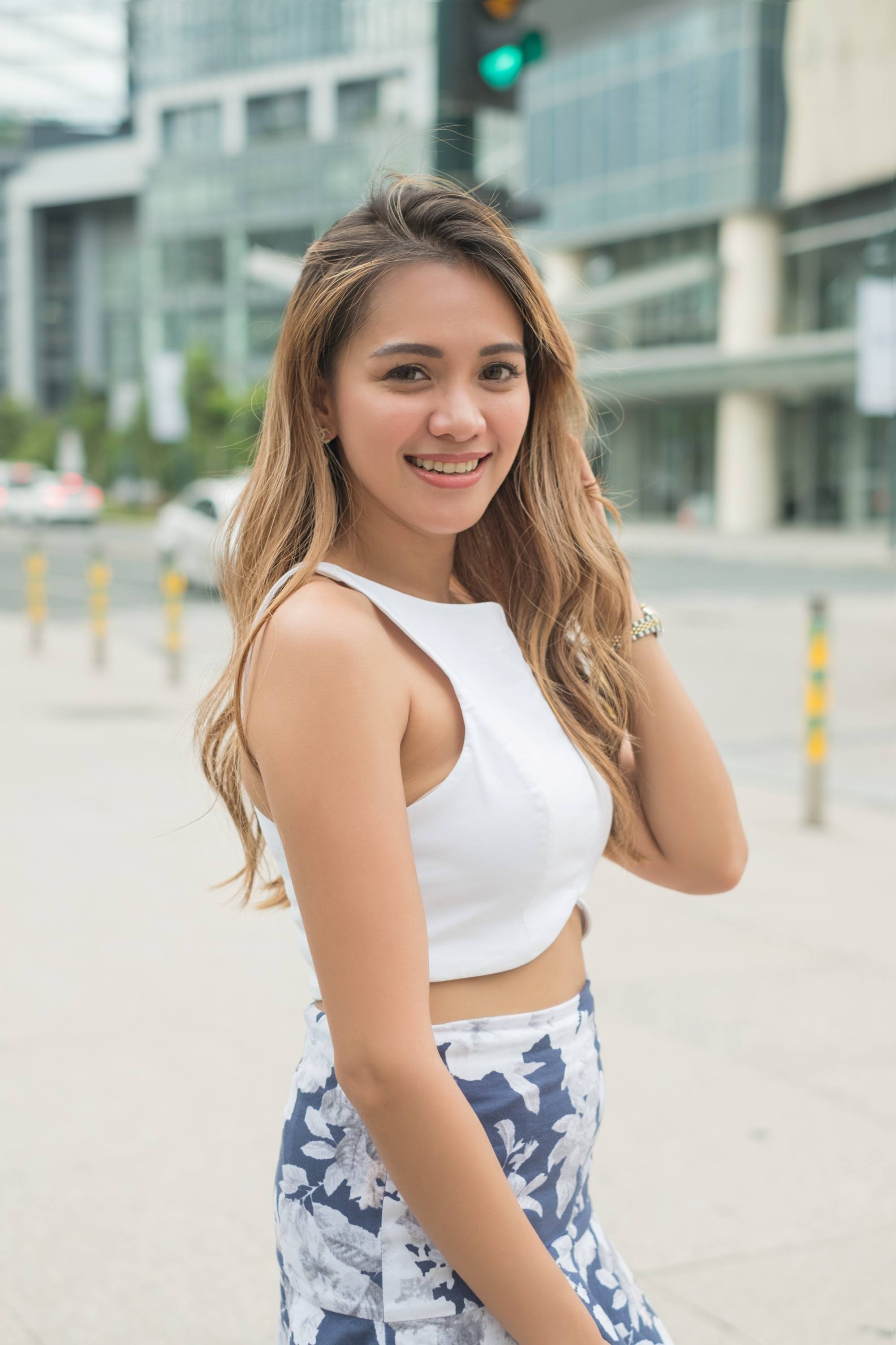 Asian woman with long wavy hair wearing a white top