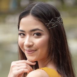 Bobby pin hair crown: Closeup shot of an Asian woman with bobby pins on her dark shoulder-length hair smiling outdoors