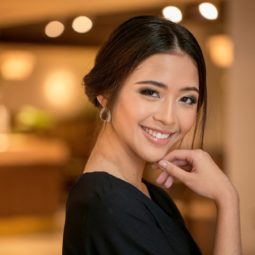 Chignon for short hair: Asian woman with dark hair in a chignon smiling in a hotel lobby