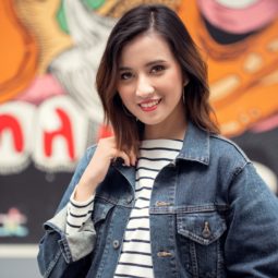 Messy layered bob: Asian woman with short dark brown hair wearing a denim jacket in front of a street mural