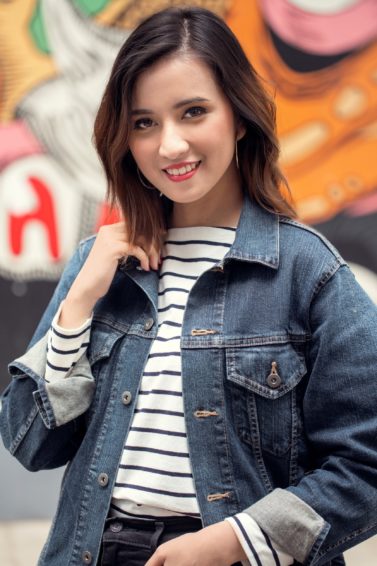 Messy layered bob: Asian woman with short dark brown hair wearing a denim jacket in front of a street mural