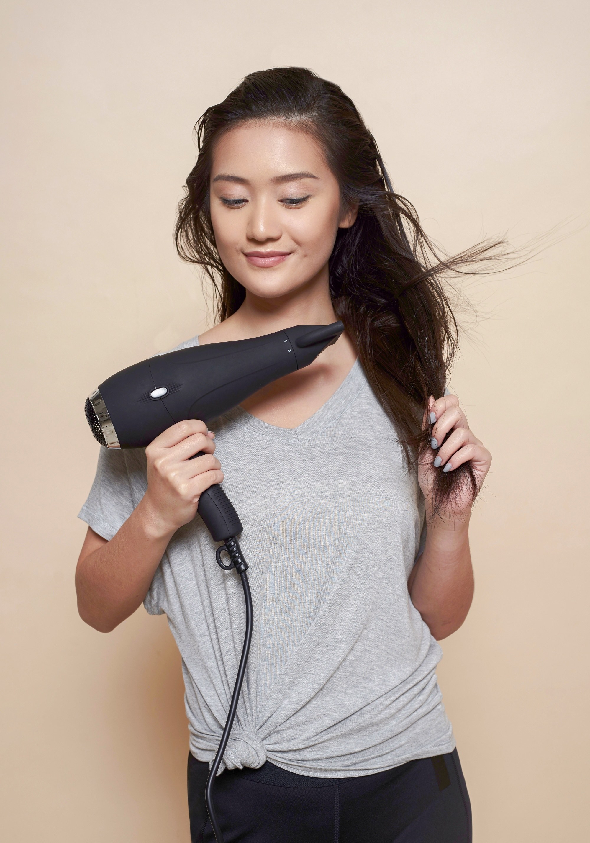 How to protect hair from pollution: Asian woman blow drying her long hair