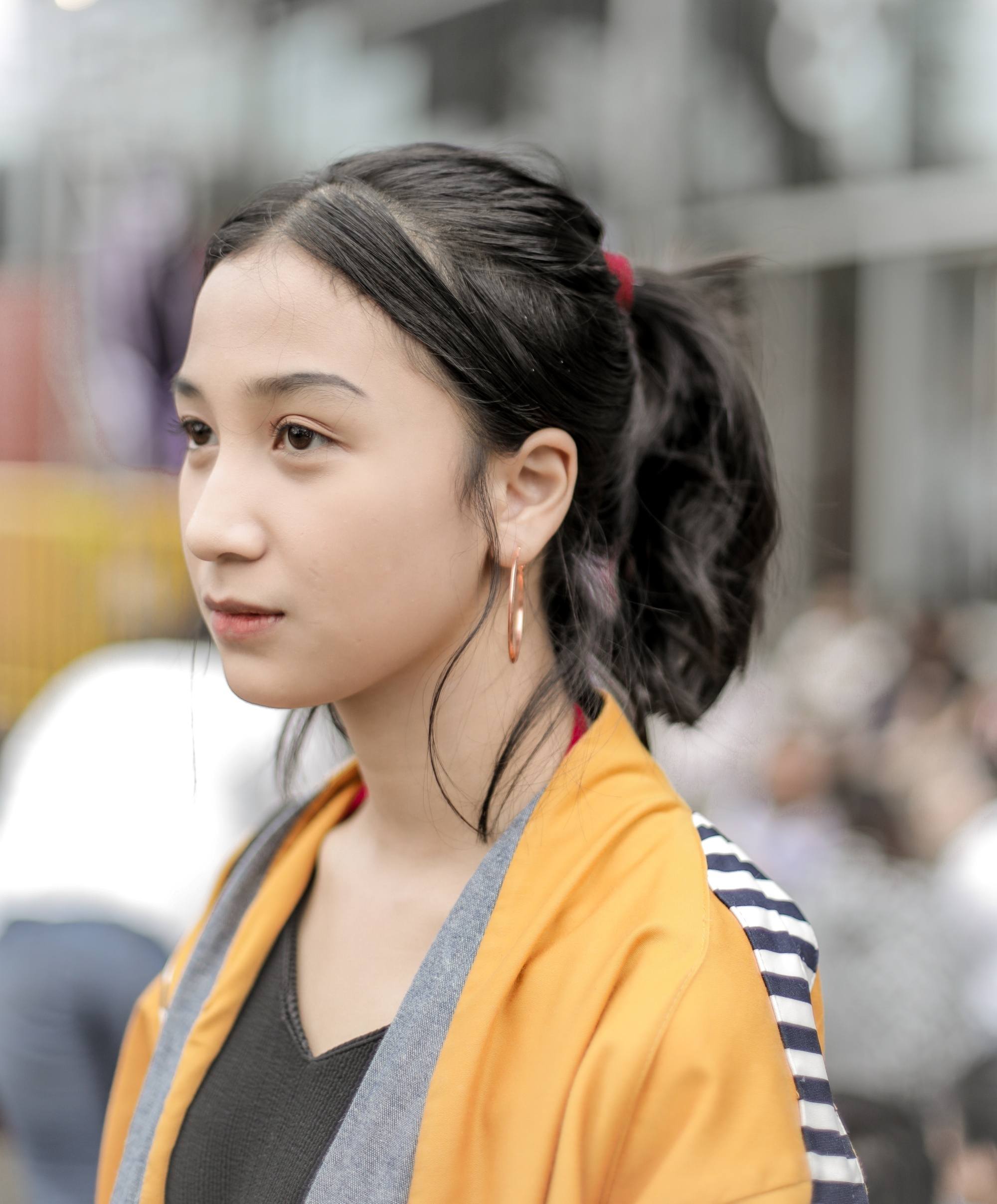 Summer updos: Closeup shot of an Asian woman with black wavy hair in a ponytail
