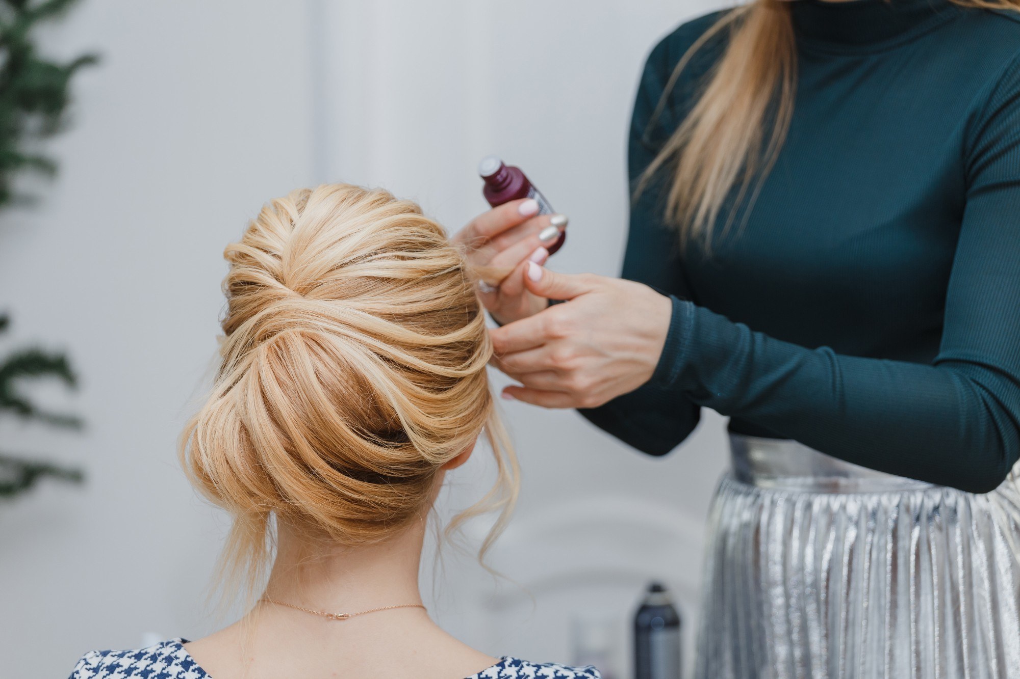 a blonde girl's back is to the camera while another person is making her French twist hairstyle