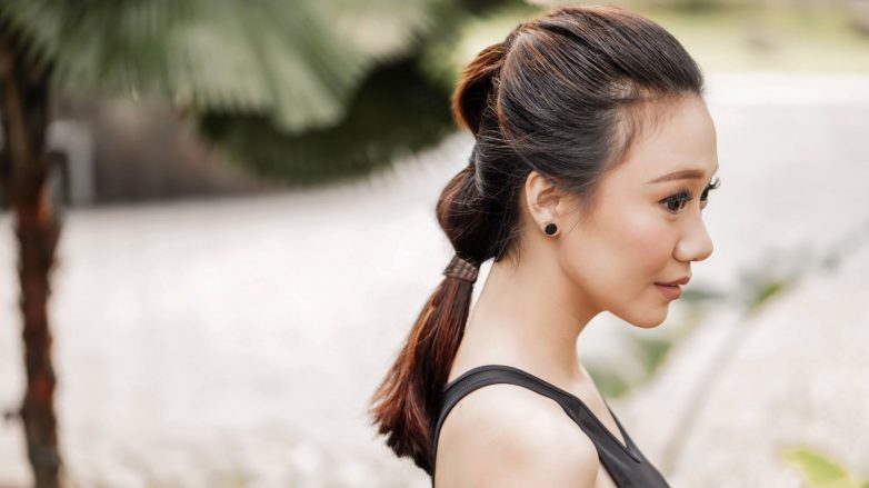 Asian woman with low bubble ponytail hairstyle wearing a black tank top outdoors