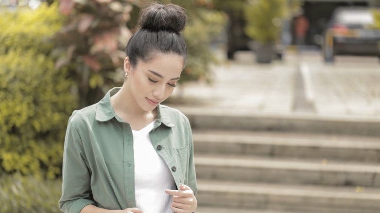 Asian woman with big top knot wearing a green jacket outdoors