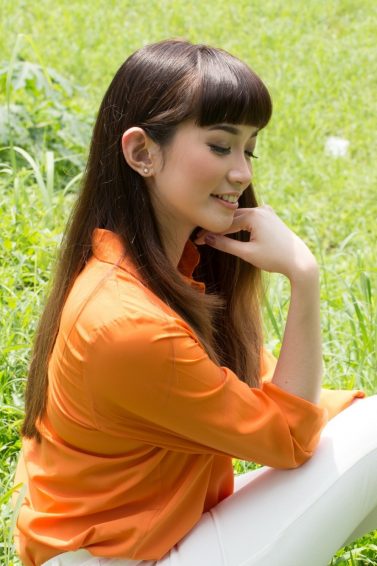 Eco-friendly hair products: Asian woman with long dark hair sitting on the grass
