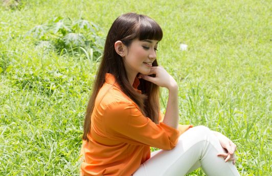 Eco-friendly hair products: Asian woman with long dark hair sitting on the grass