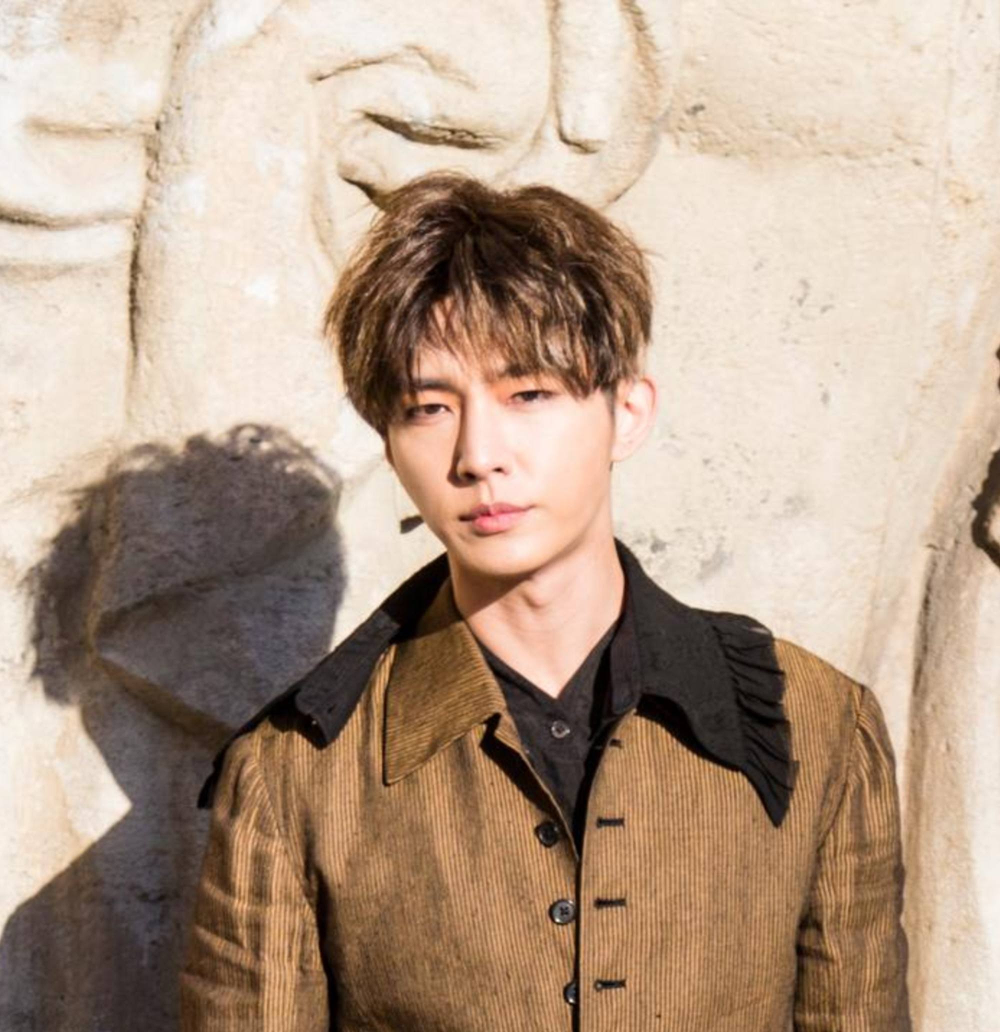 Asian guy wearing a brown jacket sports a nice haircut