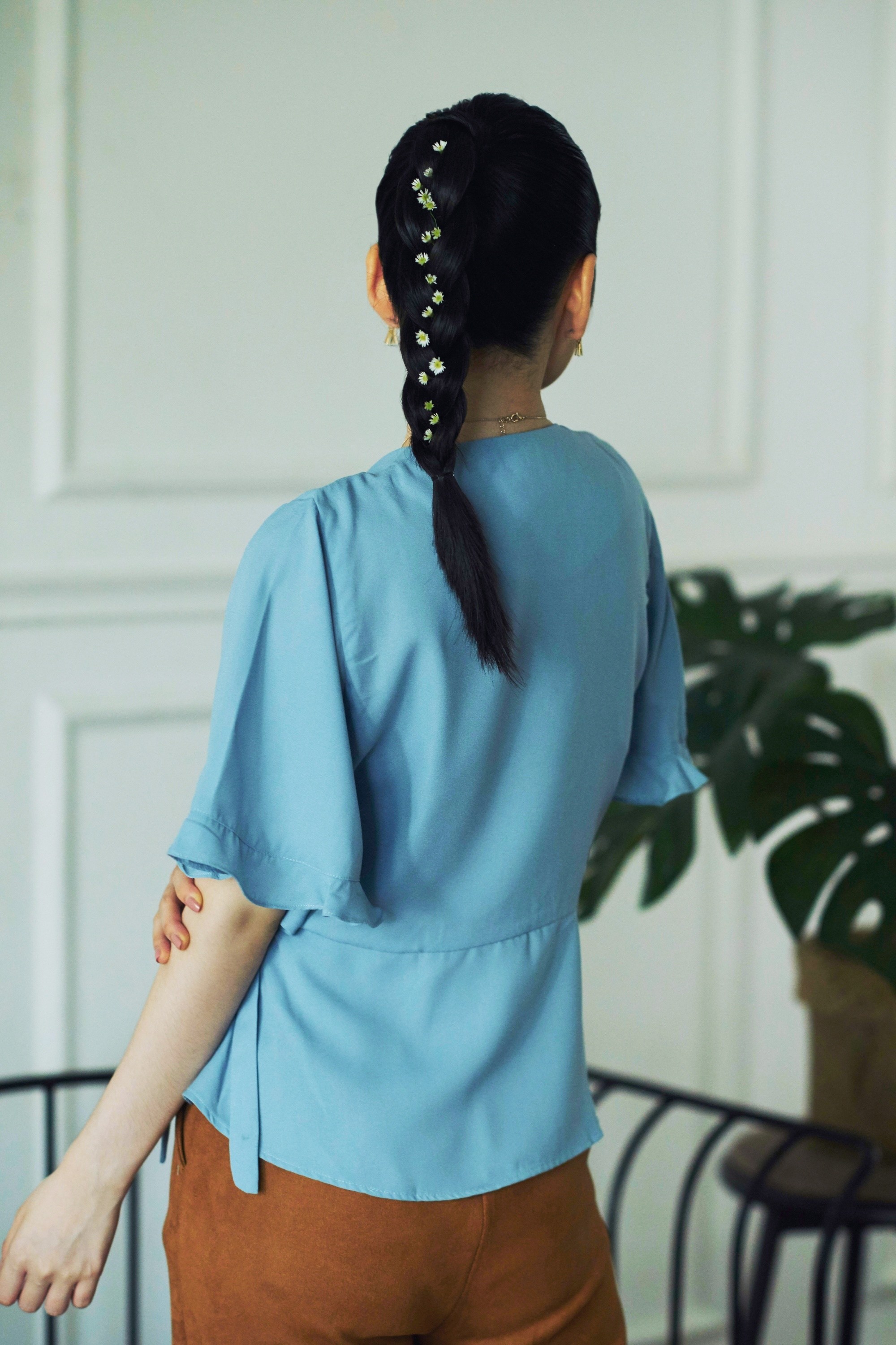 Photo arrière d'une femme asiatique avec une queue de cheval tressée portant un chemisier bleu