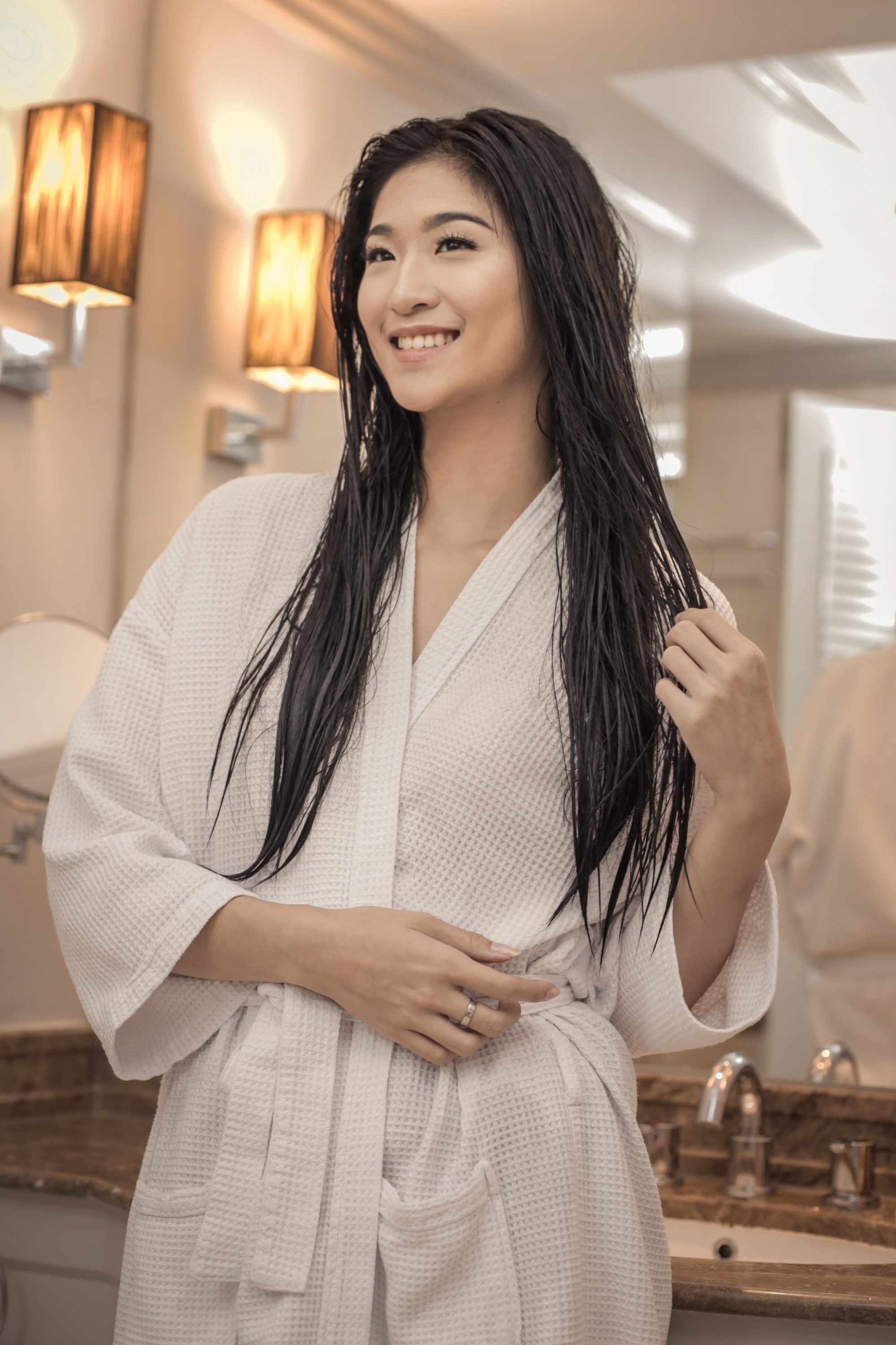 Hair vitamins: Asian woman with long damp hair wearing a white bathrobe