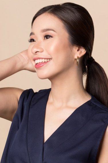 Free Gift Pass Promo: Asian woman with long dark hair in a ponytail smiling and touching her hair