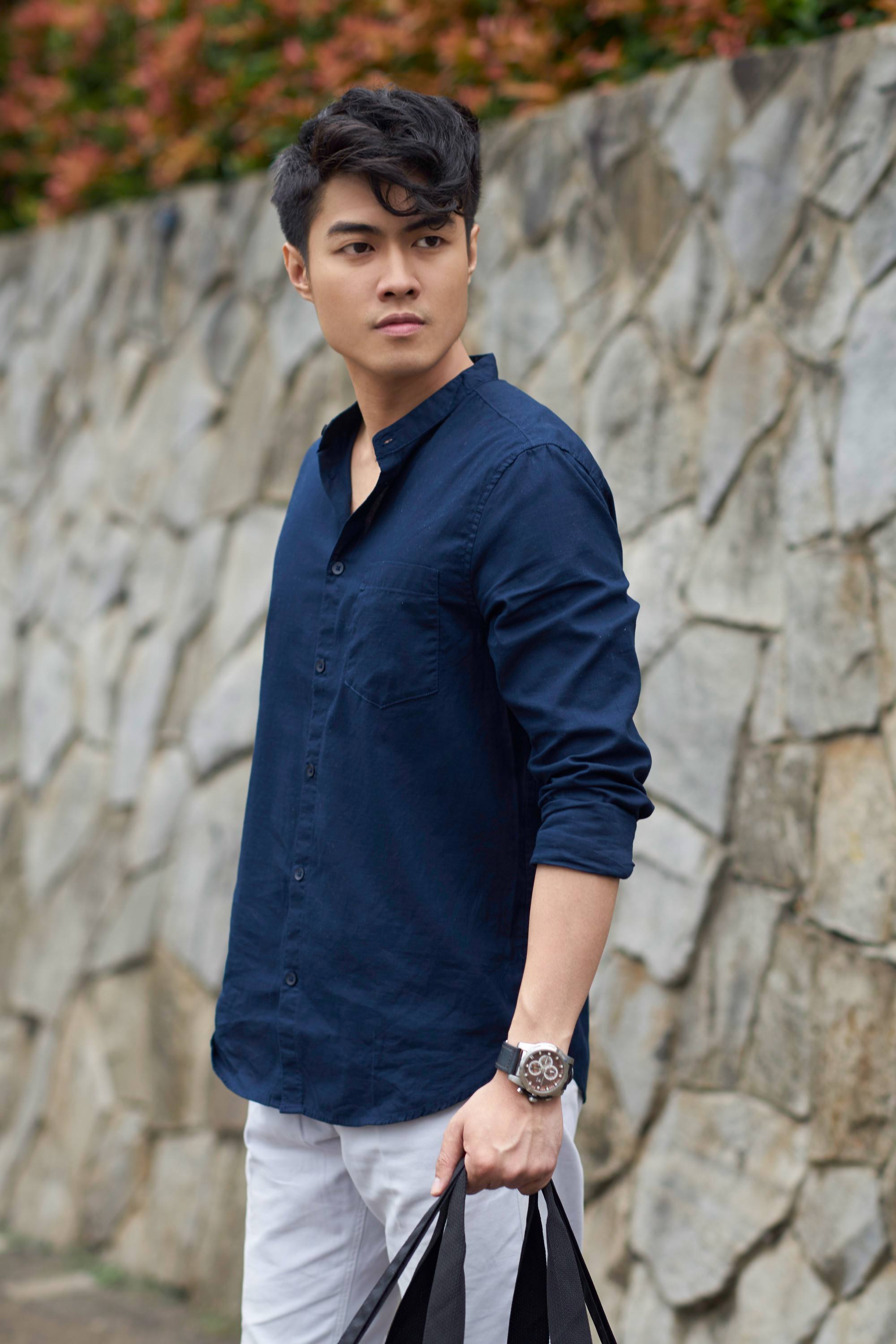 Asian guy in a blue top is looking away from the camera