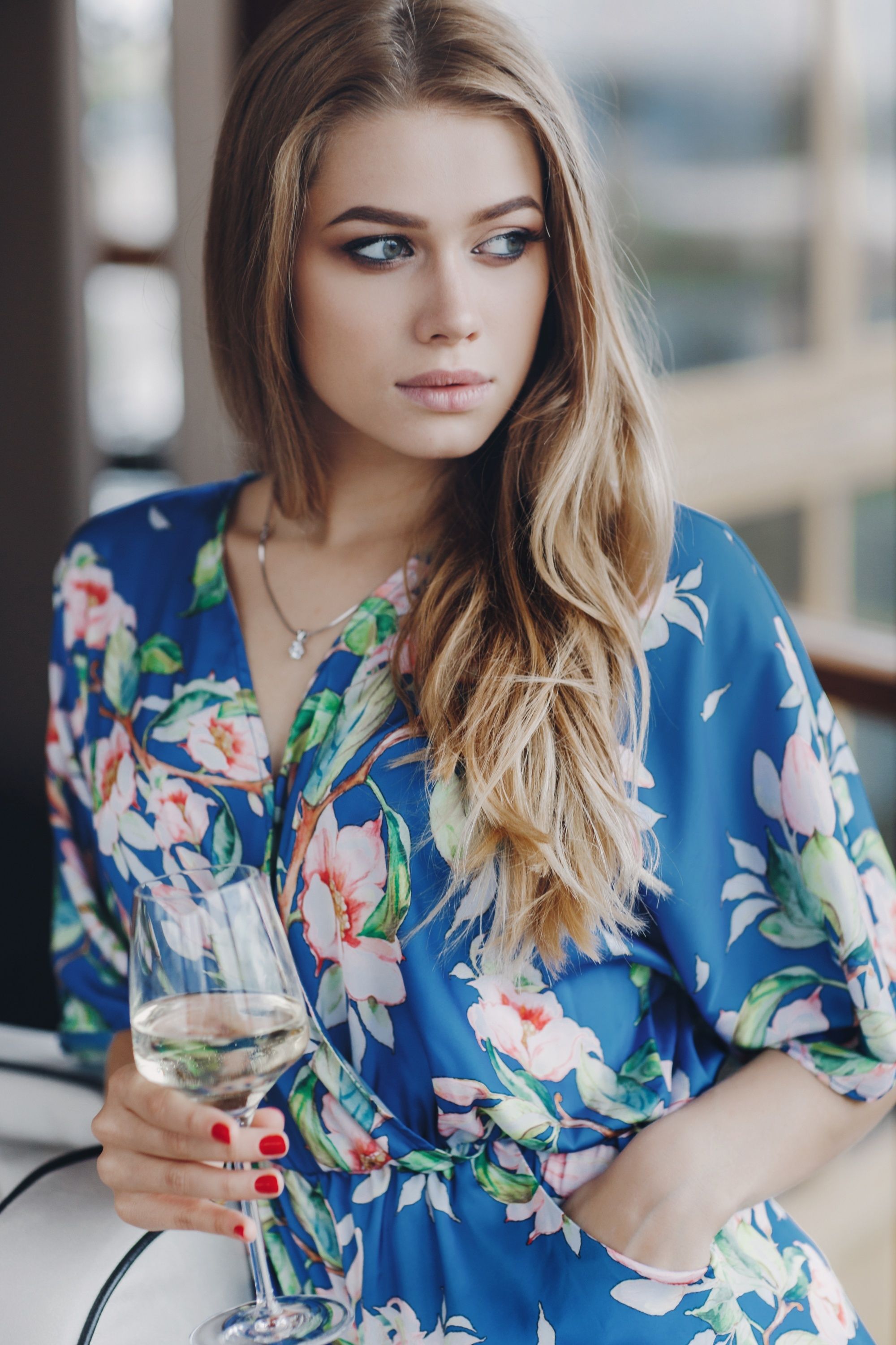 Woman with long brown ombre hair wearing a blue floral dress
