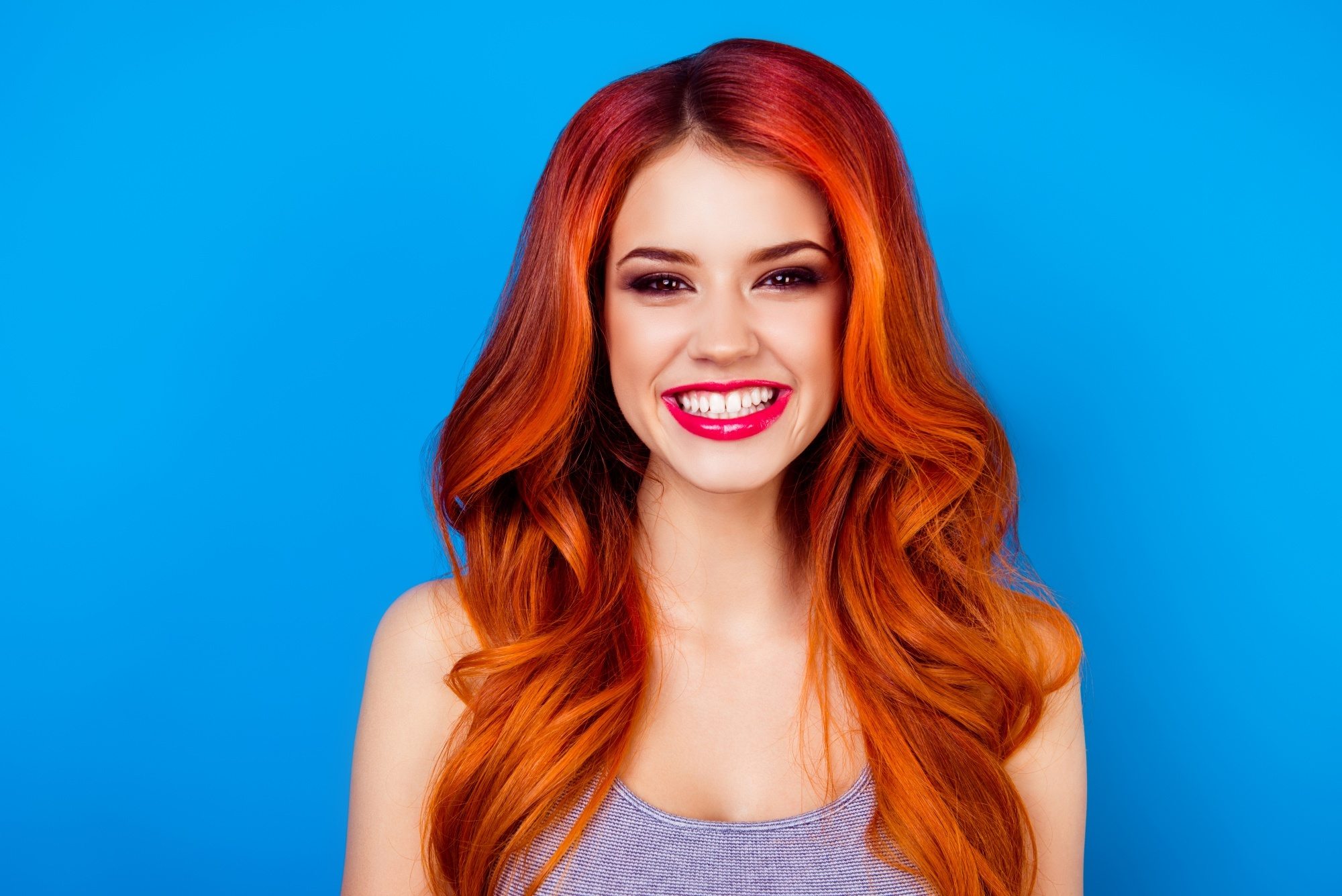 Shampoo and conditioner for colored hair: Woman with long wavy fiery red hair smiling