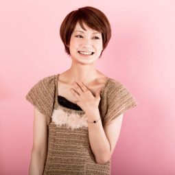 Asian woman with short apple cut haircut wearing a brown top and smiling