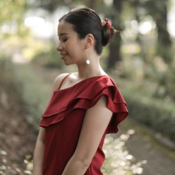 Asian woman wearing a red dress with hair in a banana clip bun standing outdoors