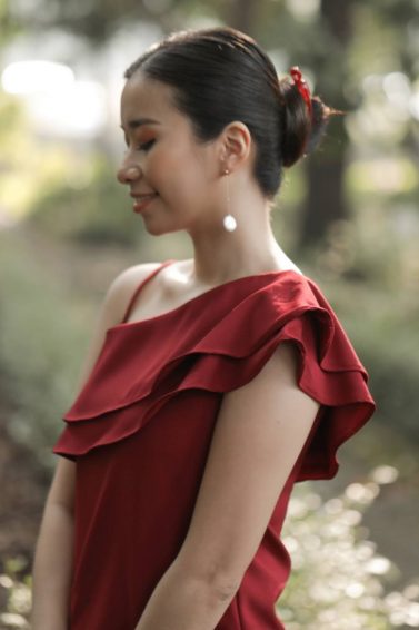 Asian woman wearing a red dress with hair in a banana clip bun standing outdoors