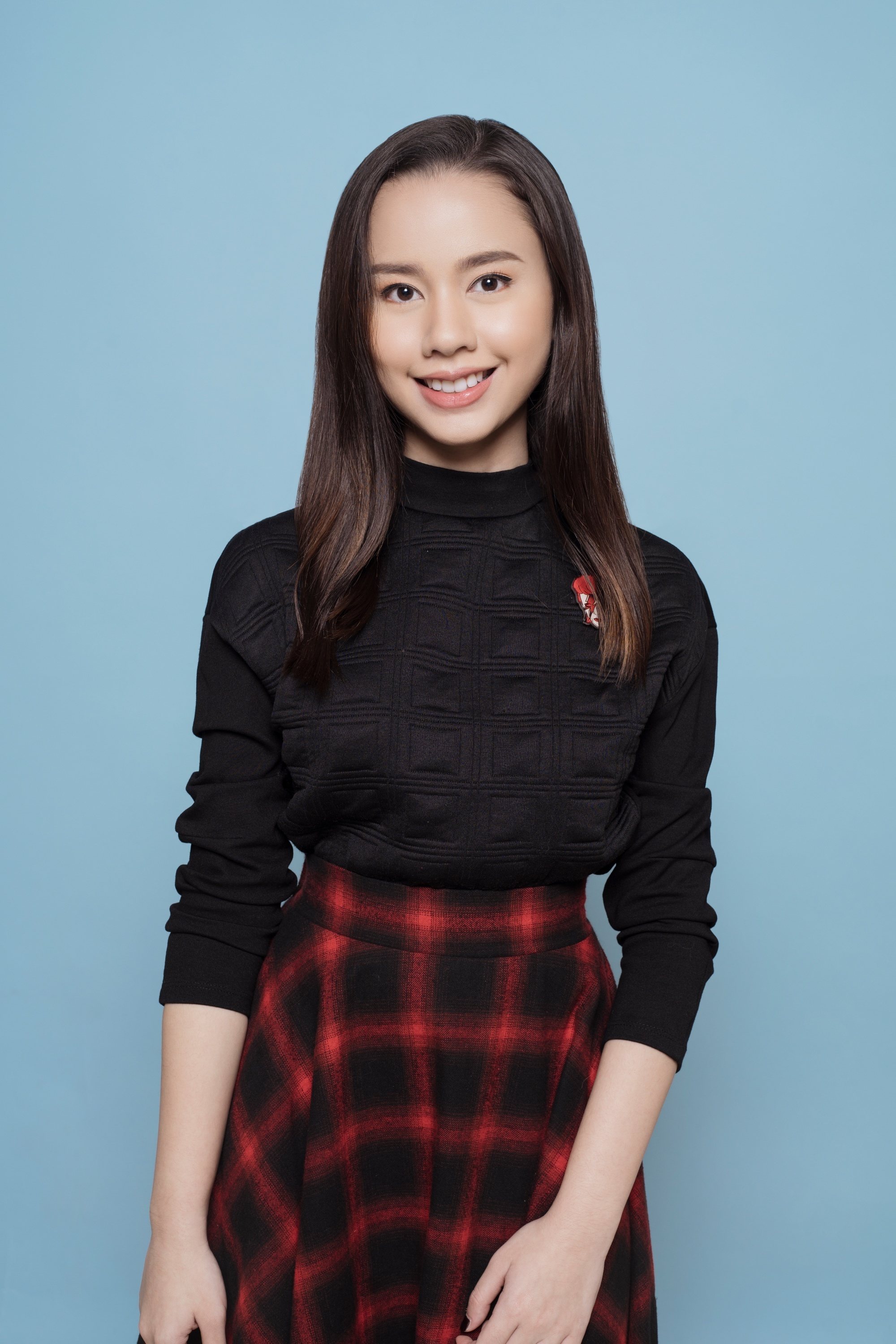 Asian woman wearing a black shirt and plaid skirt