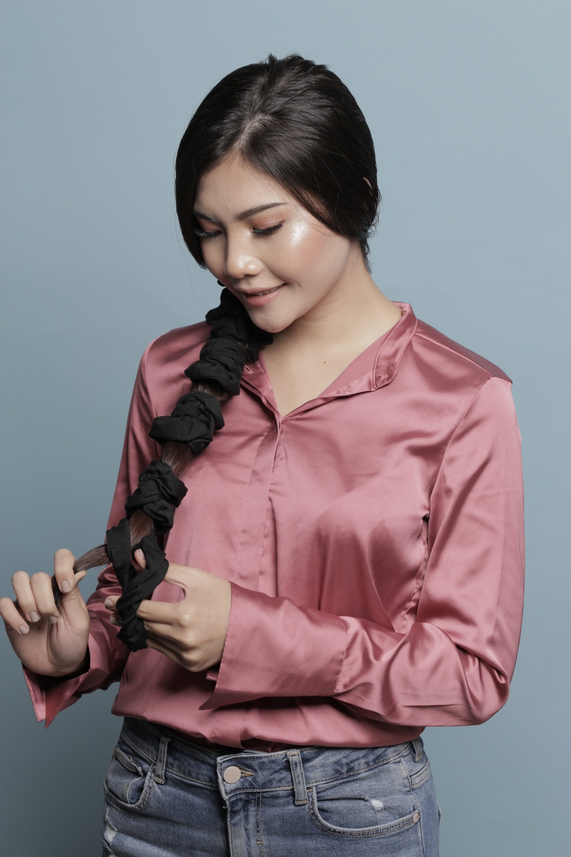 Natural hair straightener: Asian woman tying her hair using several scrunchies