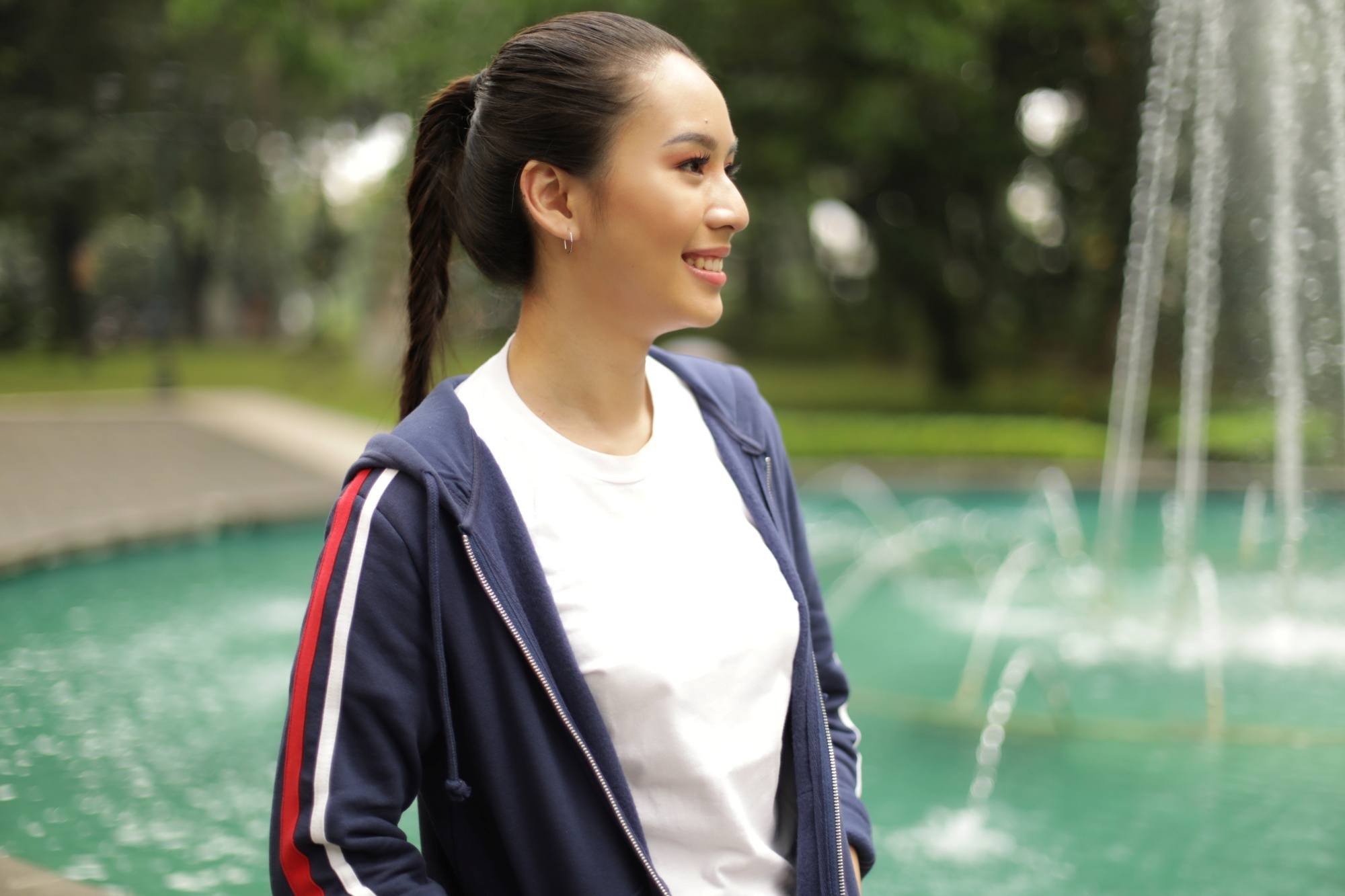 Asian woman with long hair in a fishtail braid ponytail wearing a jacket outdoors