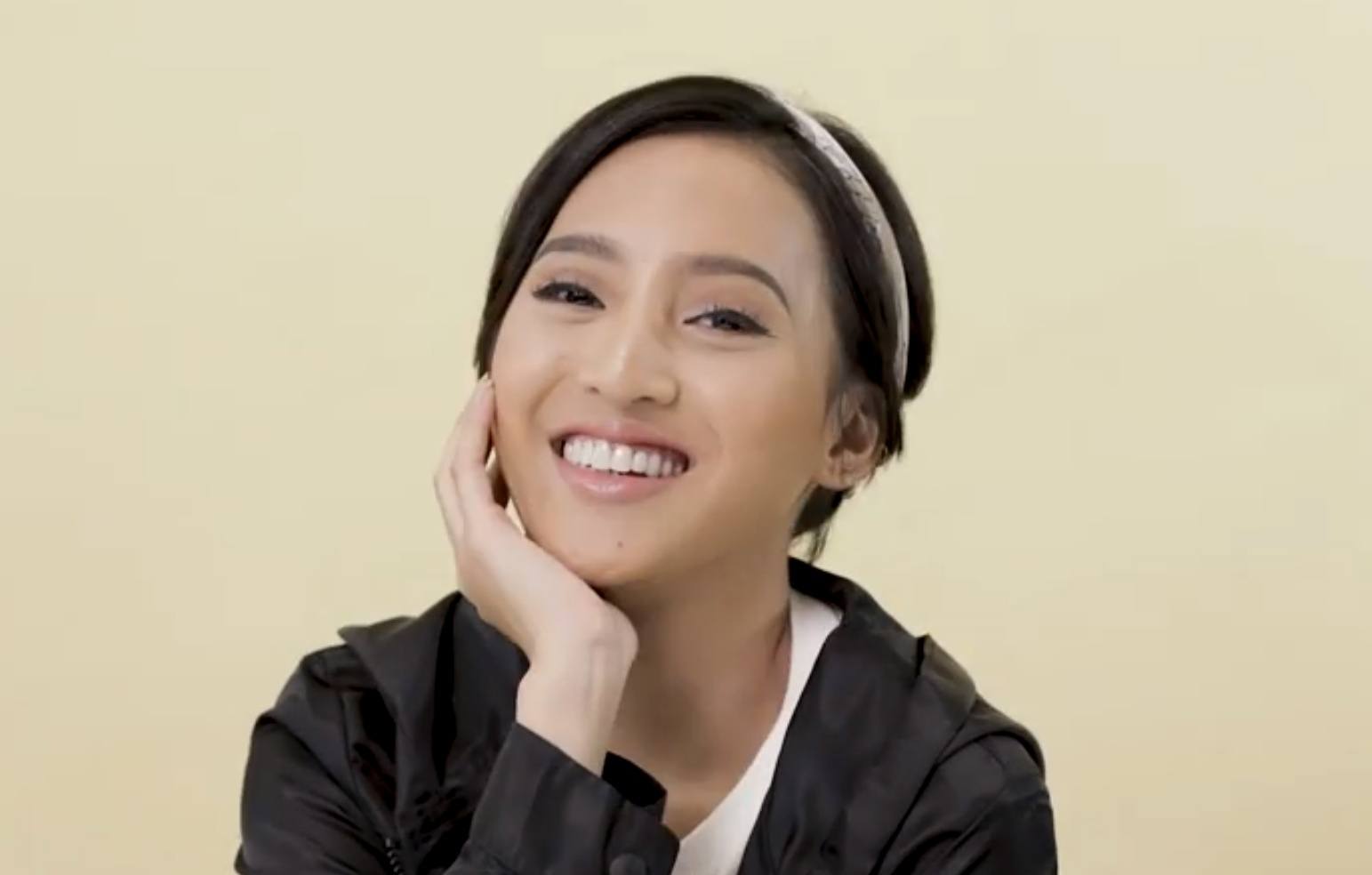 Asian woman with a pixie cut wearing a black jacket and smiling