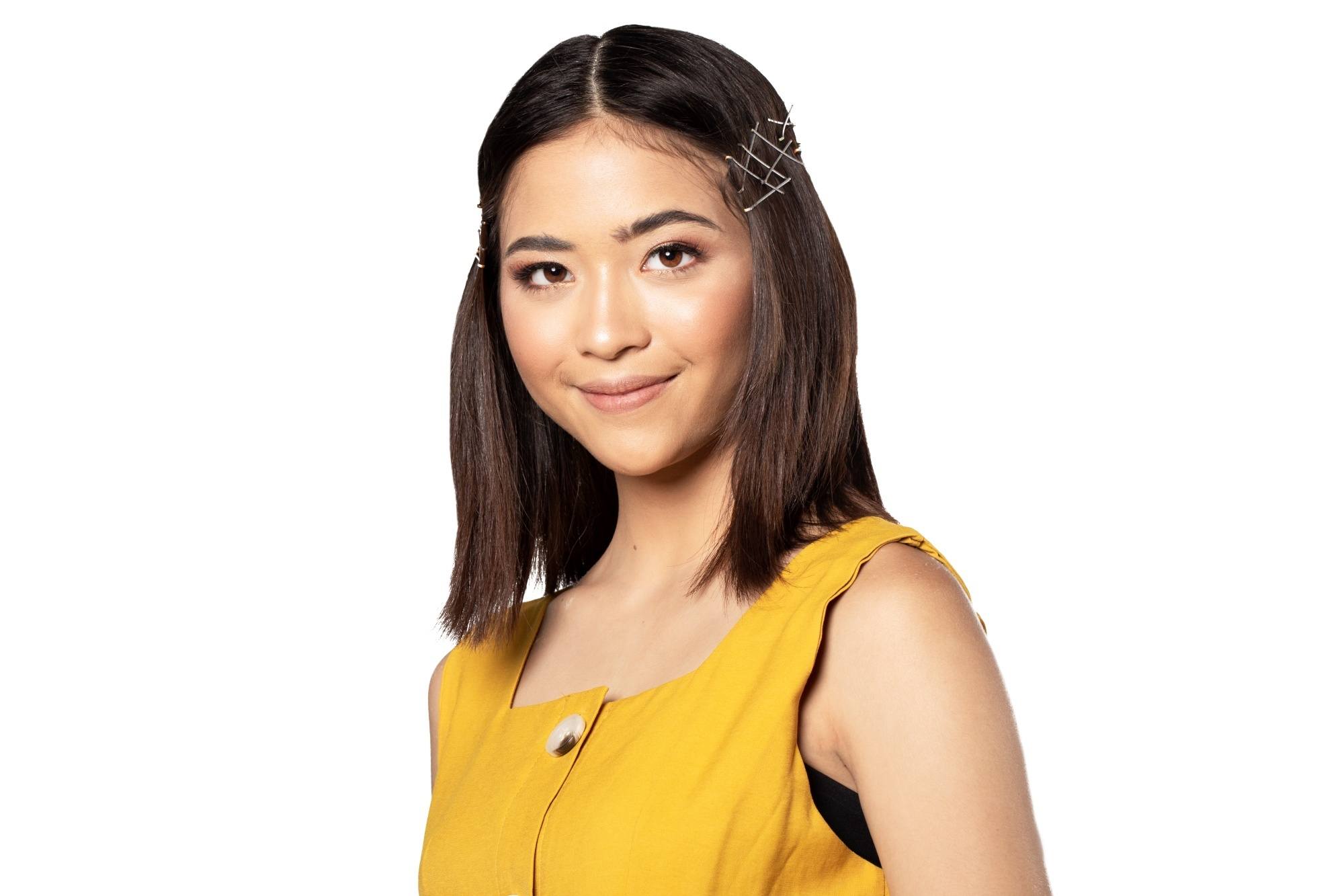 Asian woman with bobby pins on her hair wearing a yellow sleeveless top