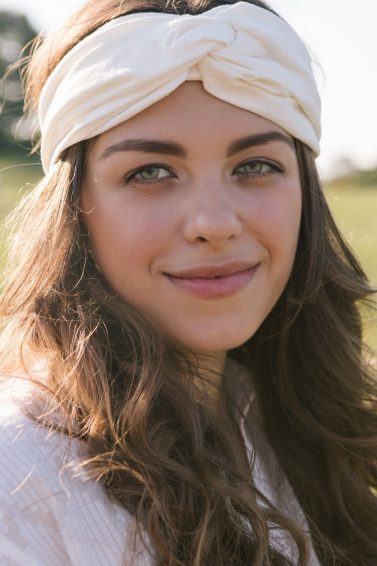 80s hairstyles: Woman with long hair with a cloth hair wrap smiling outdoors