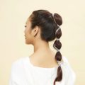 Back shot of an Asian woman with bubble ponytail wearing a white shirt
