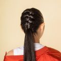 Back shot of an Asian woman with French braid ponytail wearing a red jacket