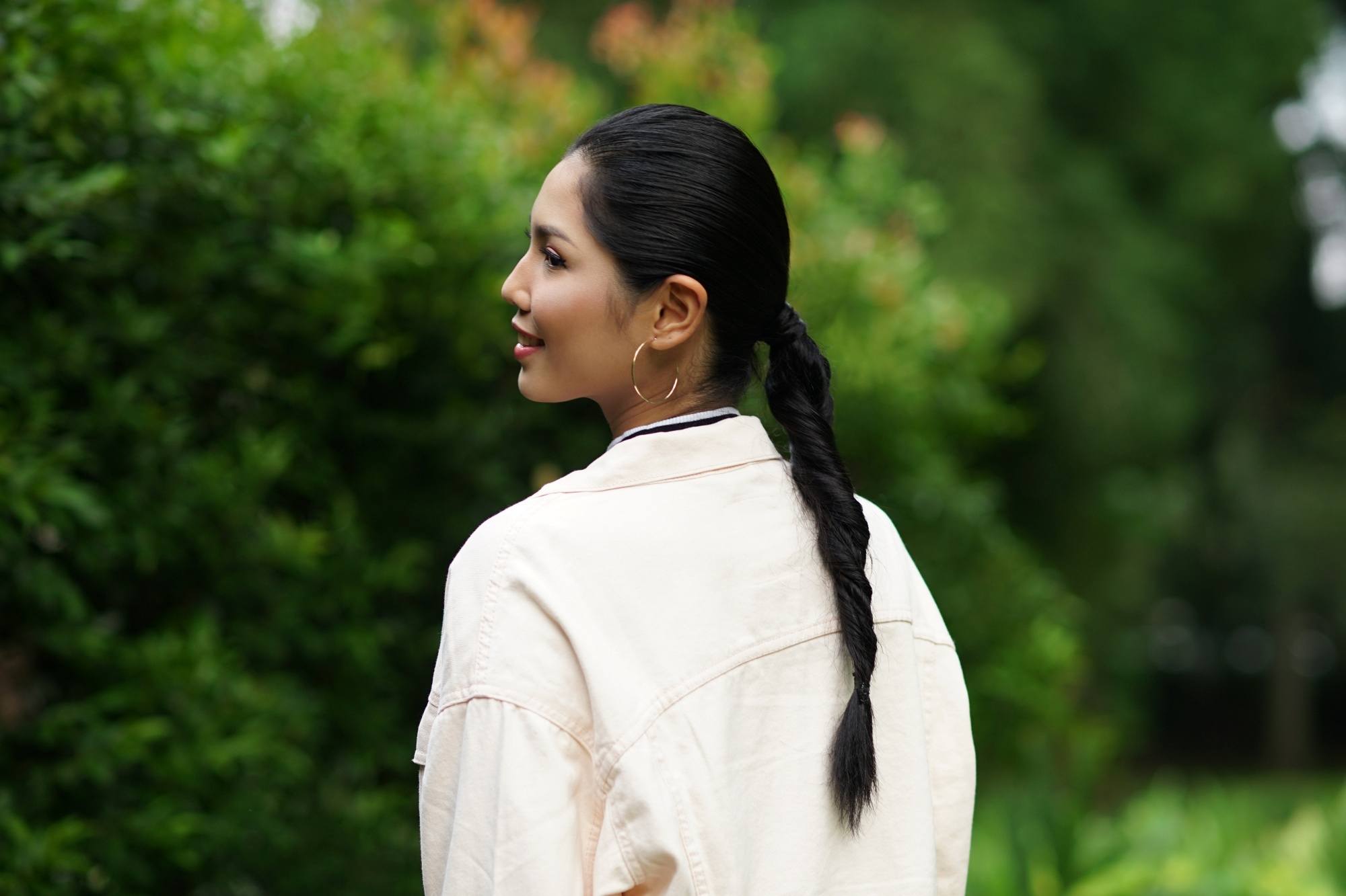 Asian woman with long black hair wearing a white jacket outdoors