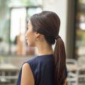 Asian woman with long dark brown hair in a vintage ponytail wearing a dark blue top