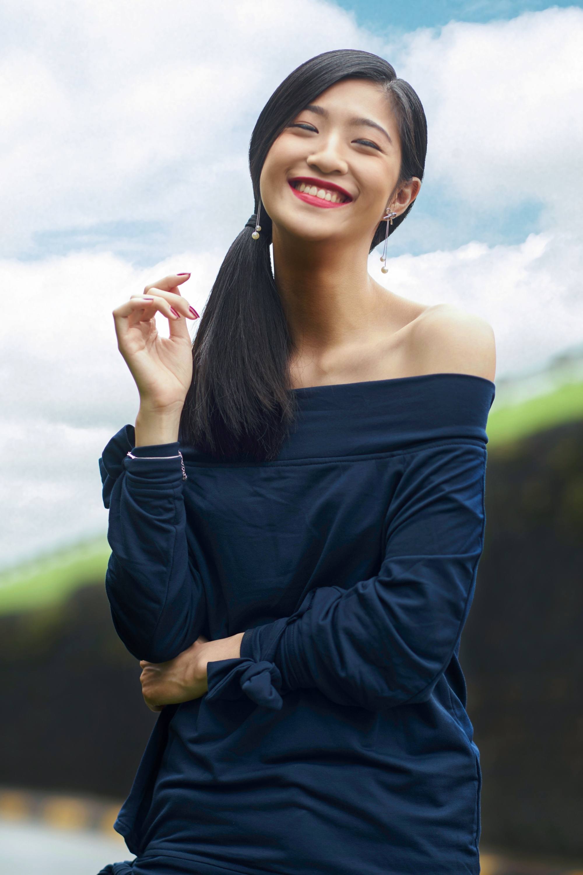 Asian woman with long black hair wearing a dark blue off-shoulder top