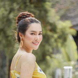 Asian woman with top bun with braid hairstyle wearing a yellow dress outdoors