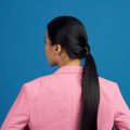 Back shot of an Asian woman with long black hair wearing a pink suitwi
