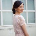 Asian woman with braided updo wearing a light pink dress outdoors