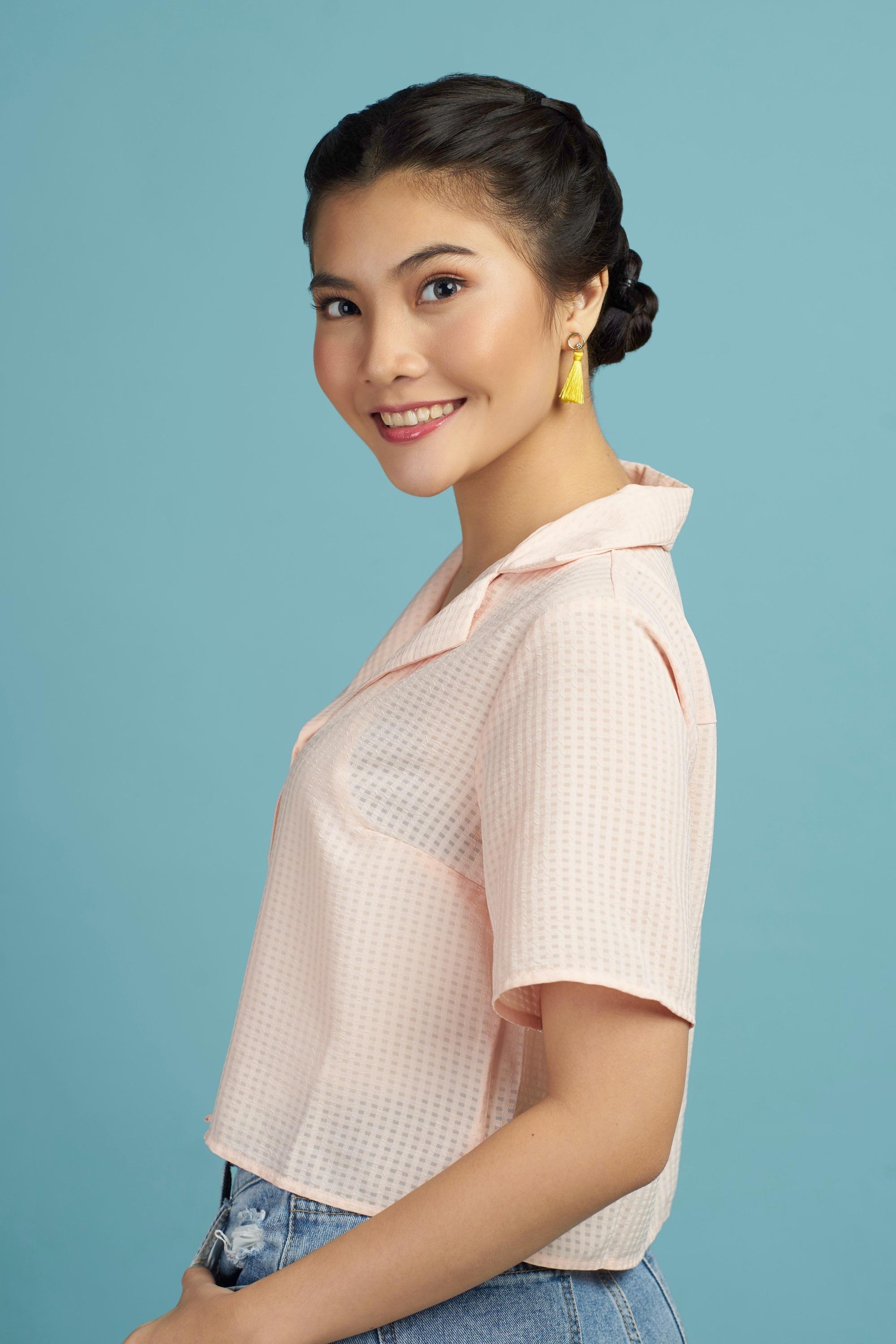 Asian woman with a Double Dutch braid bun hairstyle wearing a peach top